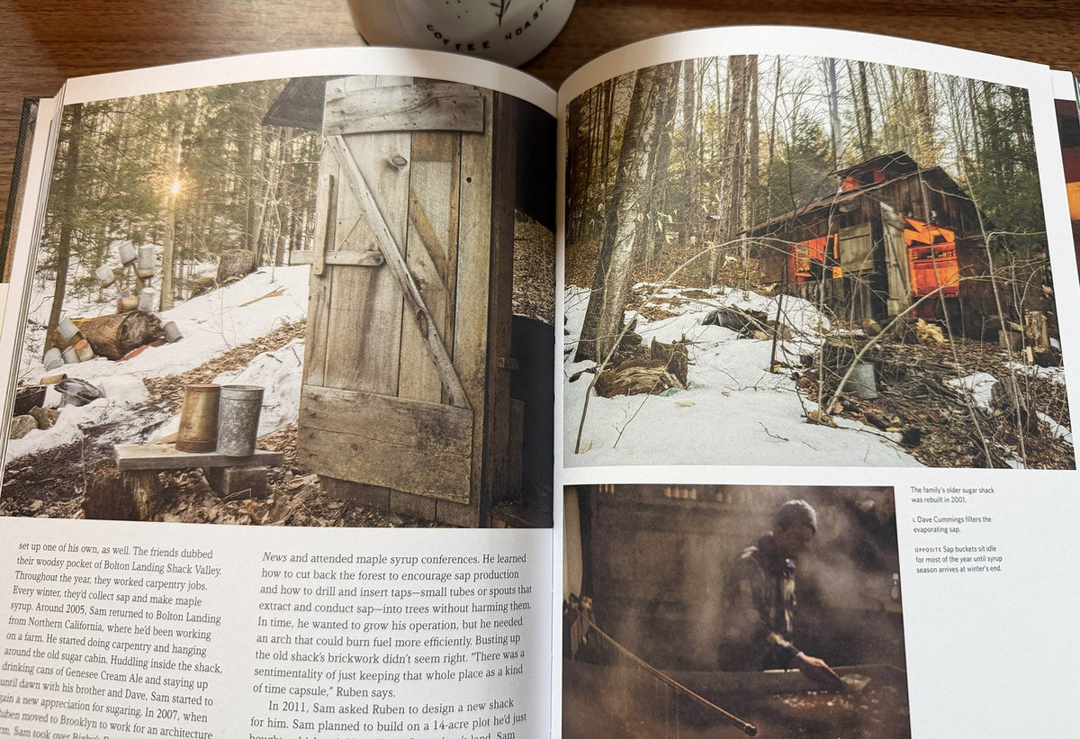 Cabin Porn open on a desk to a spread about a maple sugar shack, sap buckets in the snow and the shack glowing orange in the woods