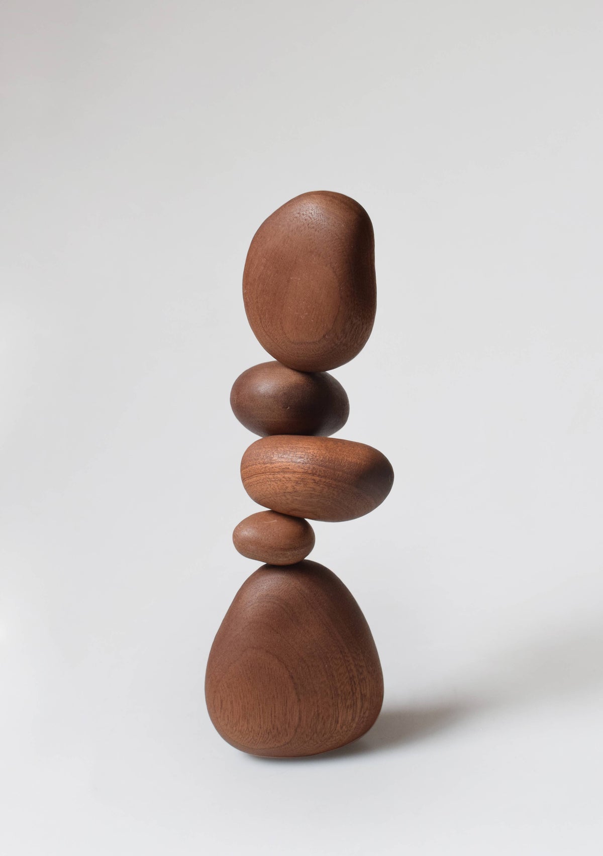 The five sapele stones balanced in a tall stack, showing the red-brown ribbon grain