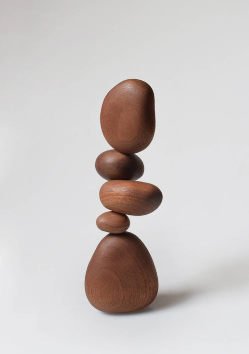 The five sapele stones balanced in a tall stack, showing the red-brown ribbon grain