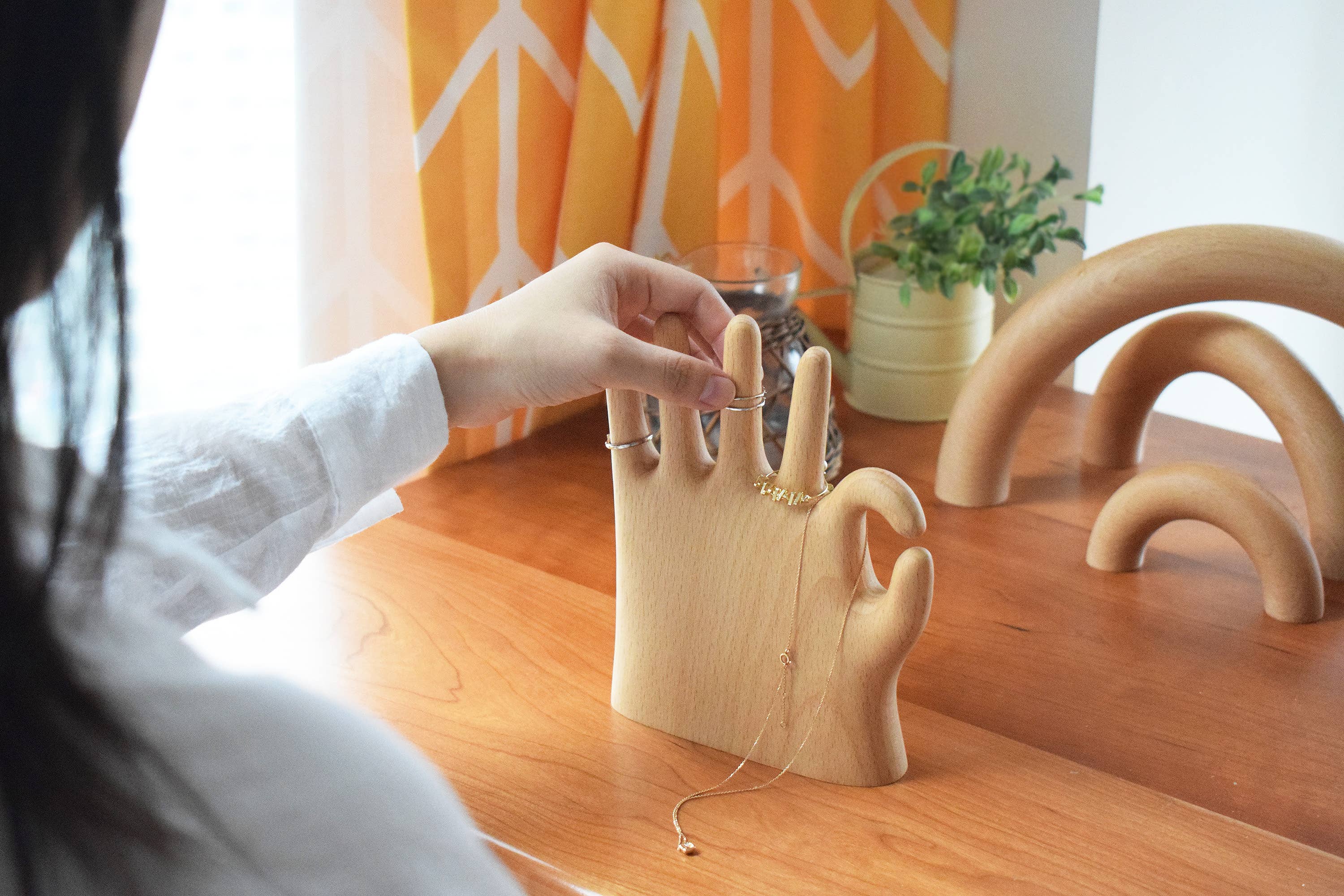 A hand lifting a ring from the wooden OK stand on a desk
