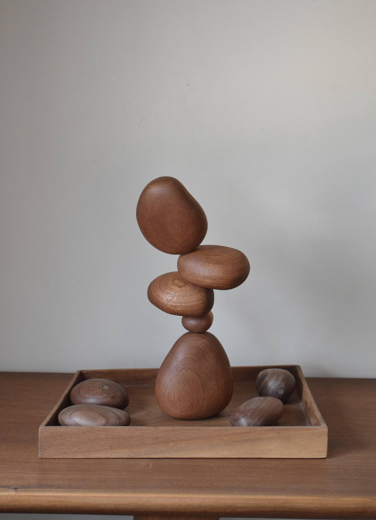 A stack of the sapele stones standing in a shallow wooden tray with the remaining stones beside it