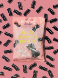 BonBon Salty Licorice Twists bag in pink on a pink ground scattered with black licorice twists