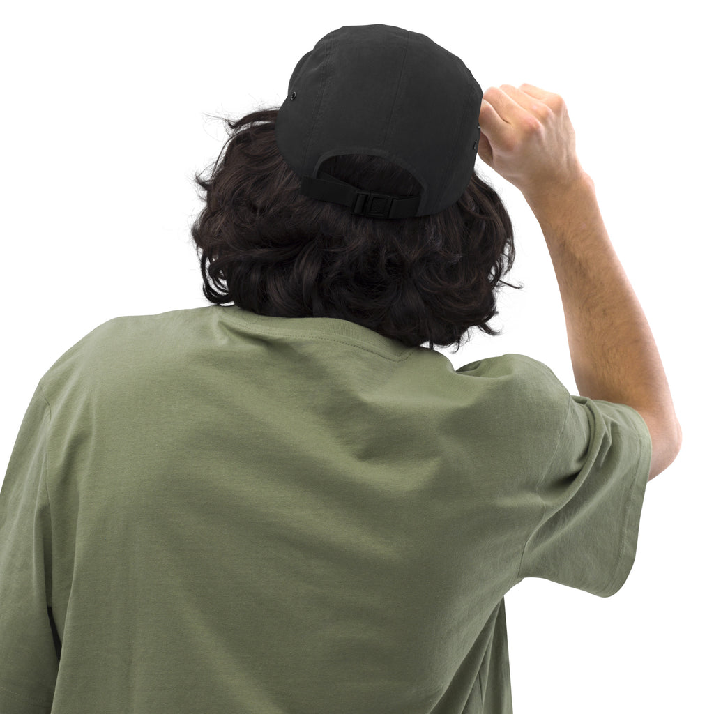 Back of the black Moss and Fog five panel cap showing the nylon strap clip closure