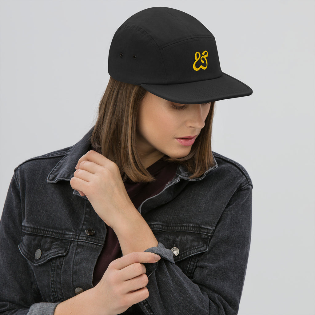 The black Moss and Fog cap face on, flat brim and gold ampersand centered on the front panel