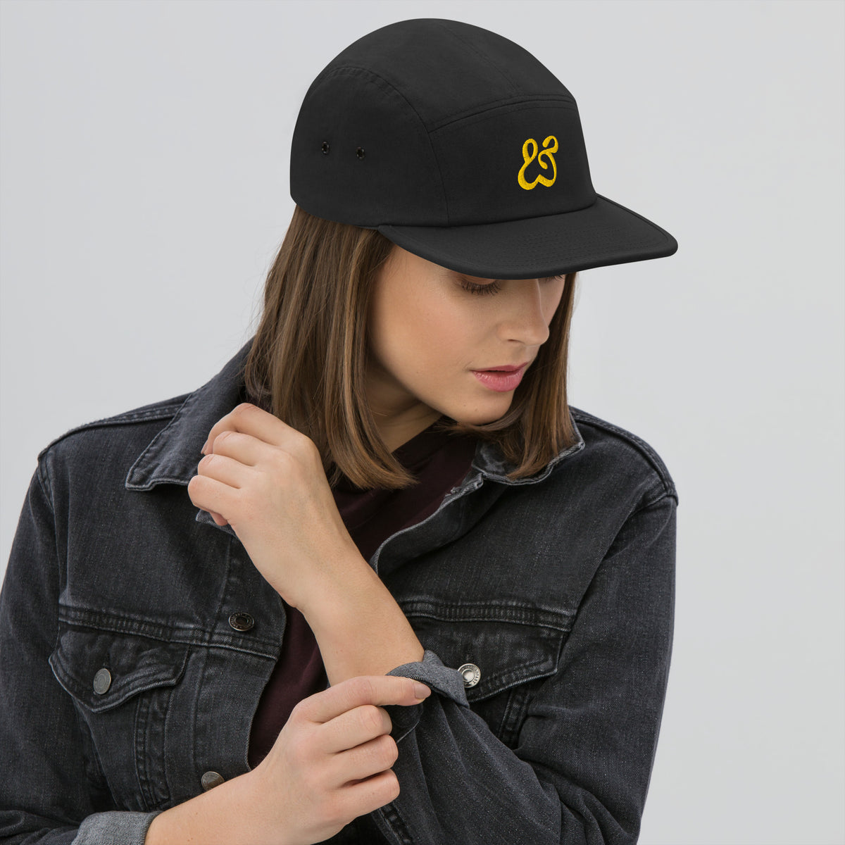 The black Moss and Fog cap face on, flat brim and gold ampersand centered on the front panel