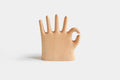 More Fingers jewelry stand in pale beech, a six-fingered hand giving the OK sign, front view on white