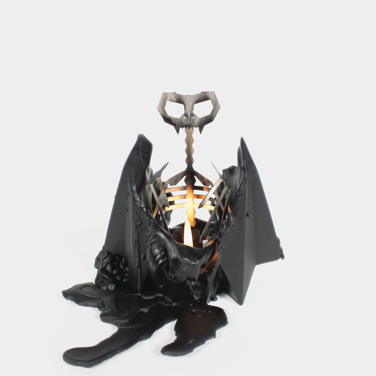 Blaka burned down to its metal skeleton, wings spread over a pool of black wax