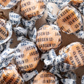 Pile of Jacobsen salted caramels twisted in white paper wrappers printed with the Jacobsen Co. name in navy