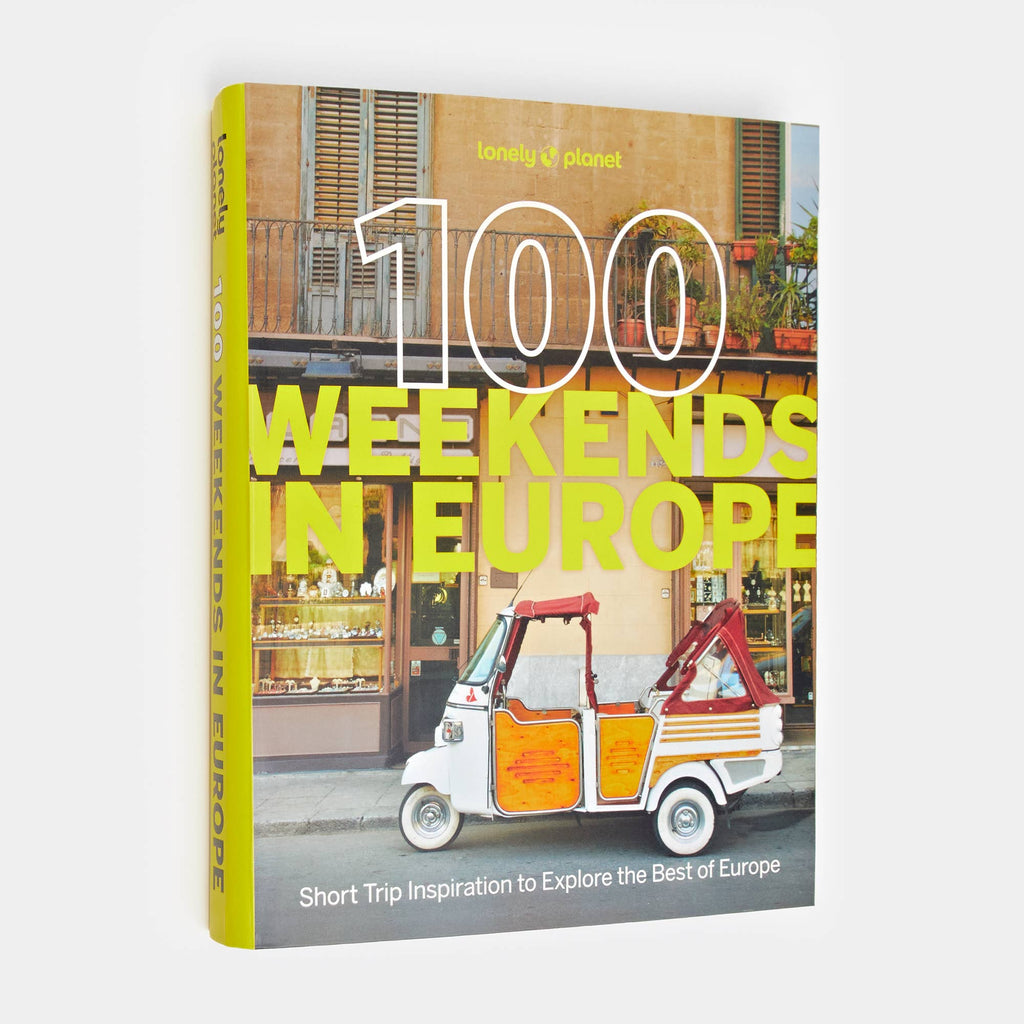 100 Weekends in Europe from Lonely Planet: a little white three wheeled van parked in front of a yellow cafe facade on the cover