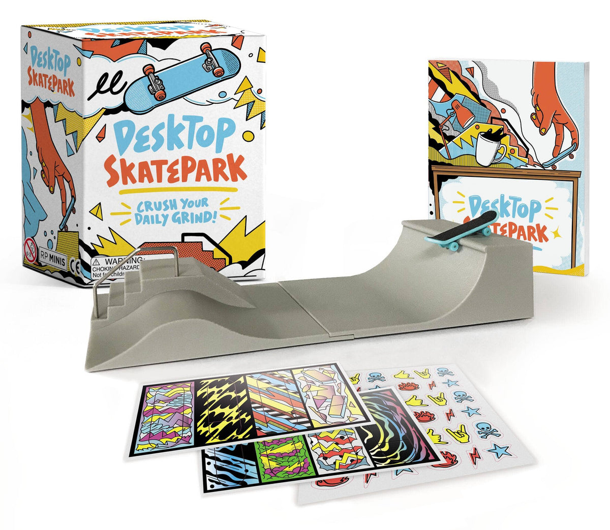 Desktop Skatepark box with a grey miniature ramp, sticker sheets and a small skateboard laid out beside it