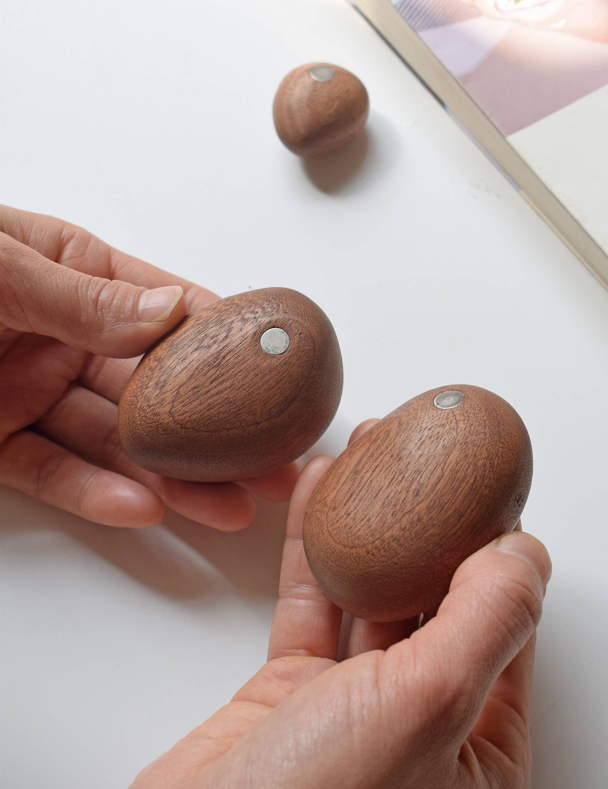 Two of the sapele stones held in the hands, showing the small inset magnets