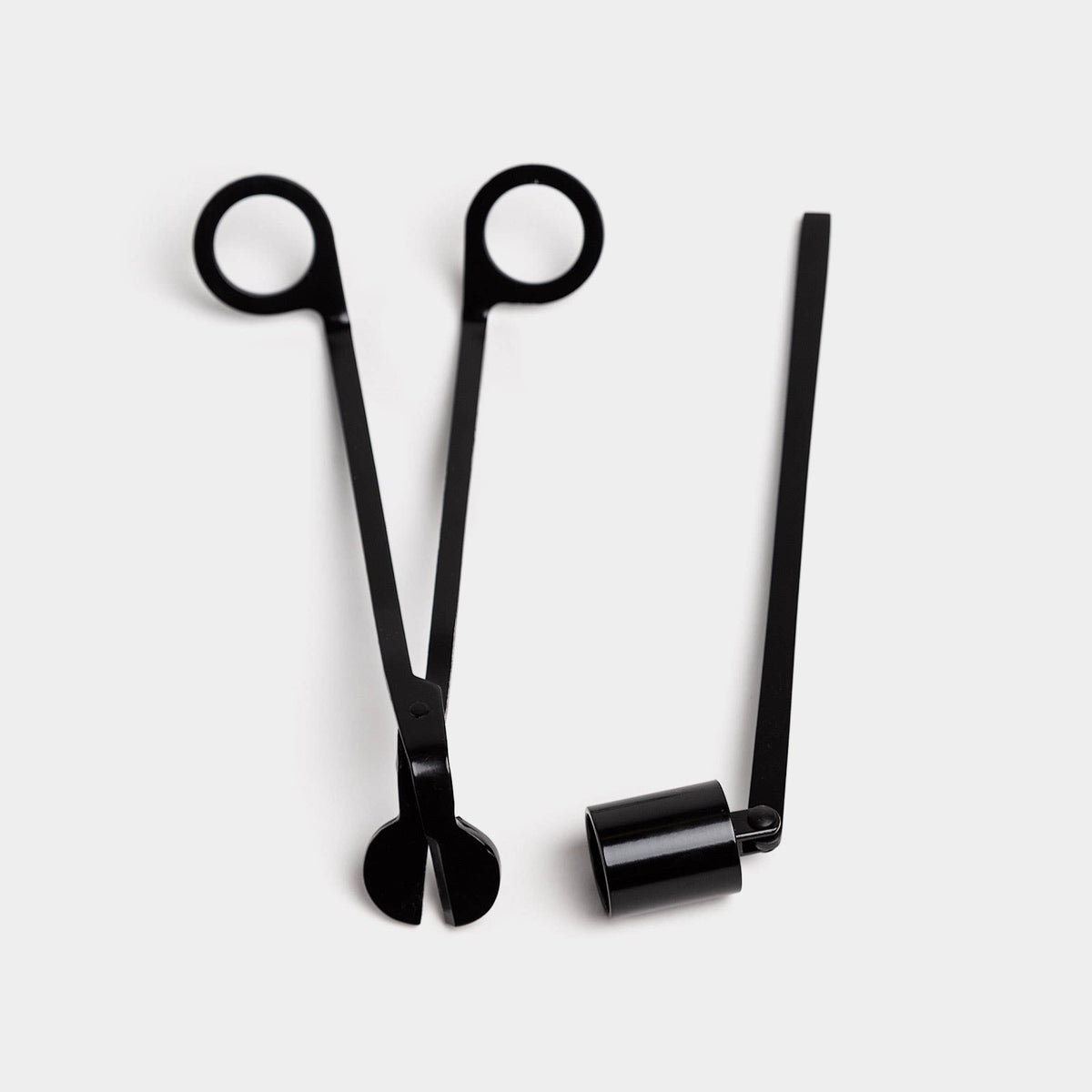The black wick trimmer and bell snuffer side by side on a white ground