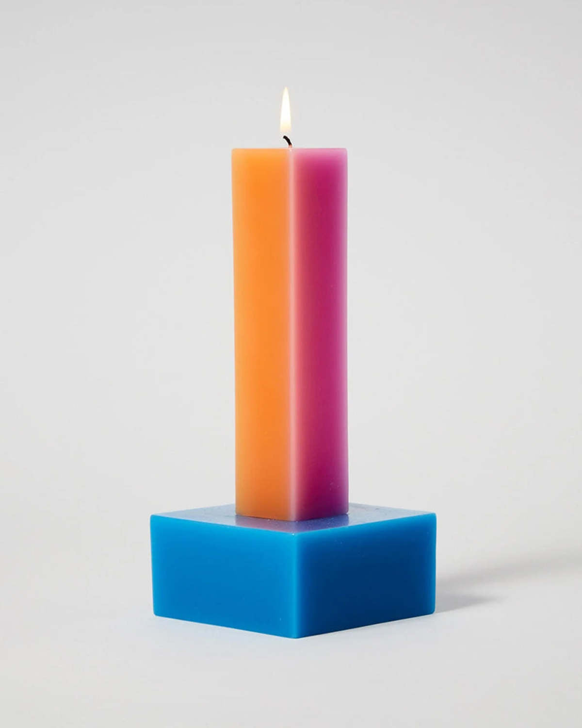 Happiness 2 pillar candle lit, an orange and pink column on a square blue base