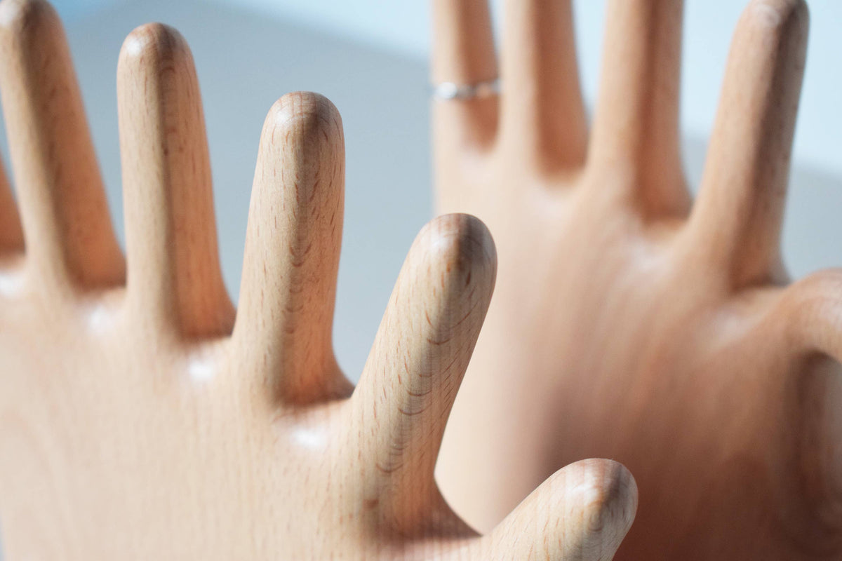 Close view of the smooth beech grain running up the fingers, with a thin ring near one fingertip