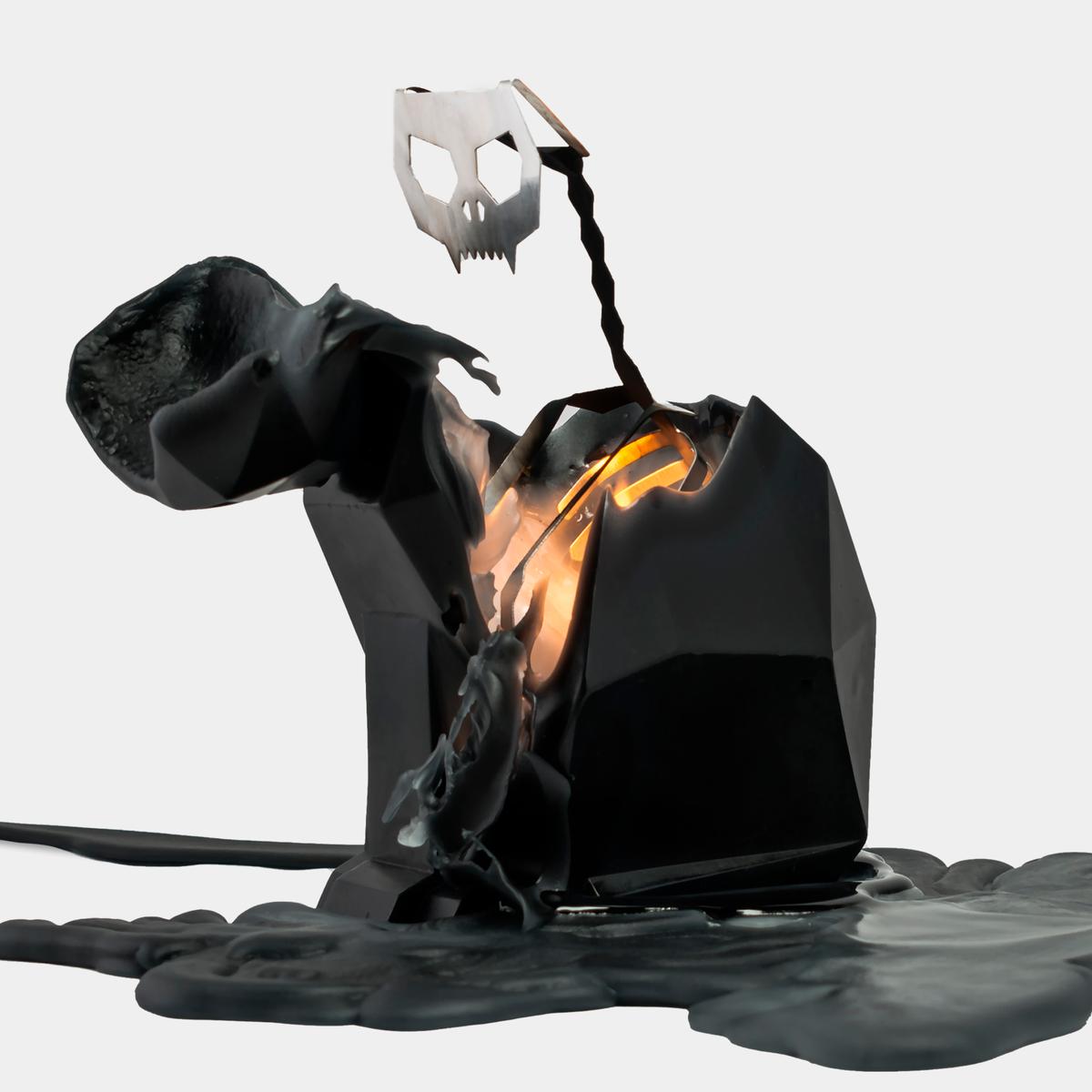 Kisa candle half burned, wax pooled on a plate with the metal skull and spine exposed