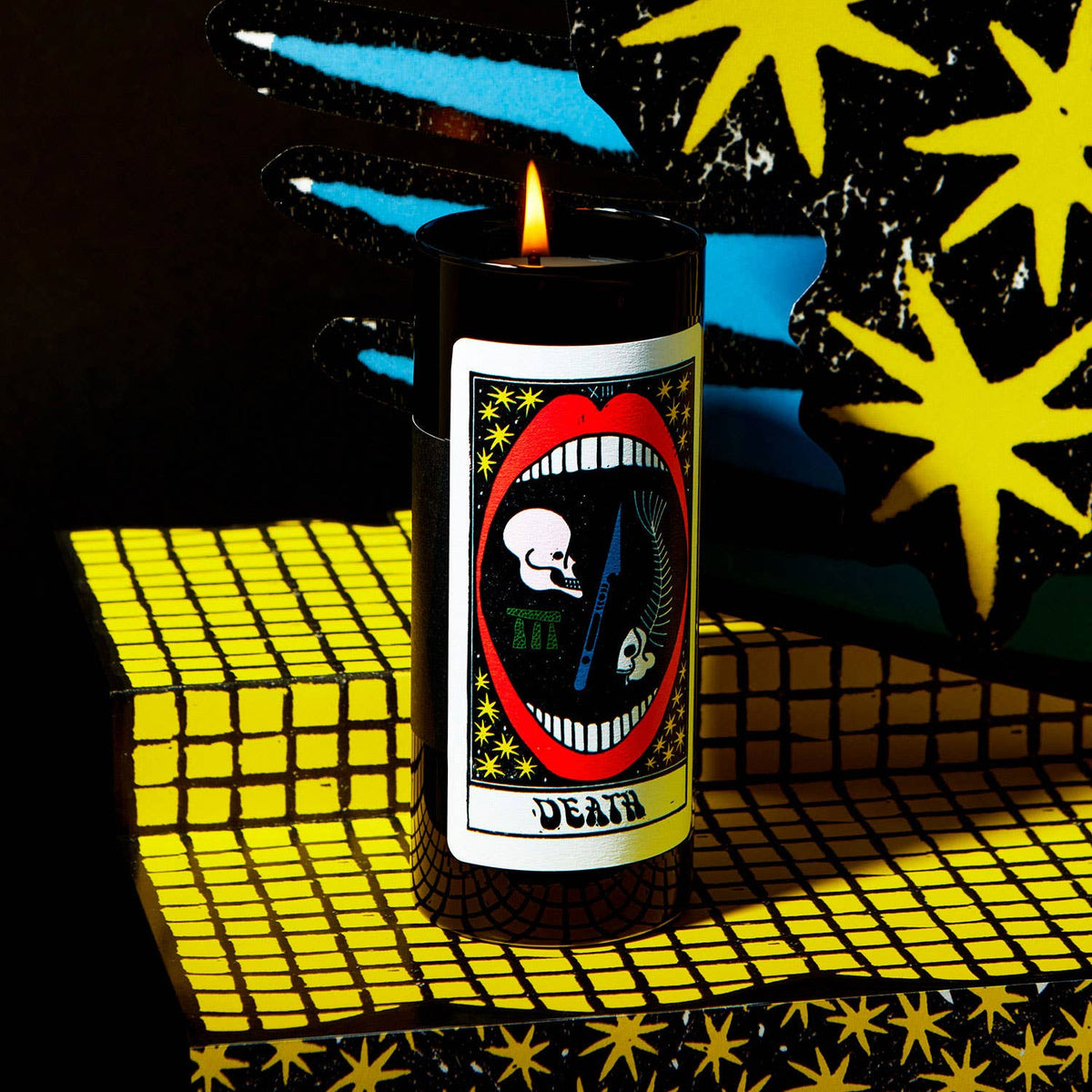 Tarot Candle, Death, burning on a yellow grid ground with cut paper stars