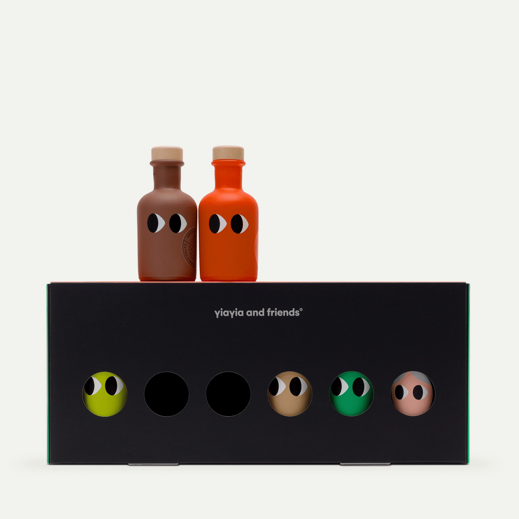 Yiayia and Friends olive oil gift box, black with six round windows showing colorful bottles with cartoon eyes, two bottles standing on top