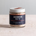 Jar of Jacobsen Cherrywood Smoked Salt, 2.39 oz, with a navy label and white lid on a pale stone table