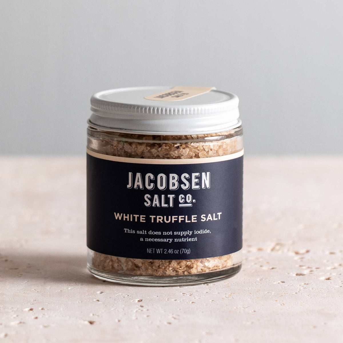 Jar of Jacobsen White Truffle Salt, 2.46 oz, with a navy label and white lid on a pale stone table