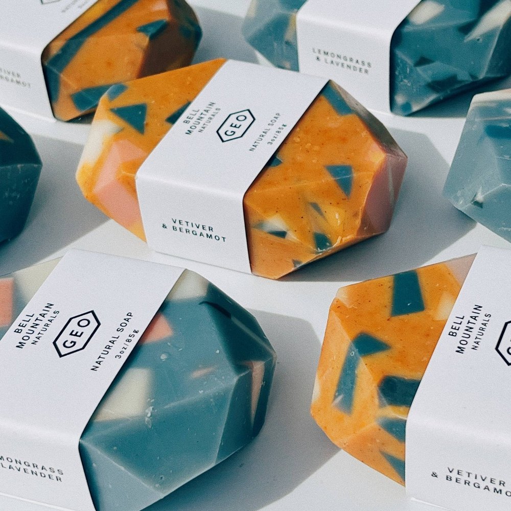 Faceted terrazzo soap bars in teal and amber, wrapped in paper bands
