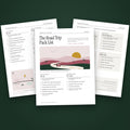 Three pages of The Road Trip Pack List fanned on moss green, the first page showing a small rose colored car on a winding road through pink hills at sunset